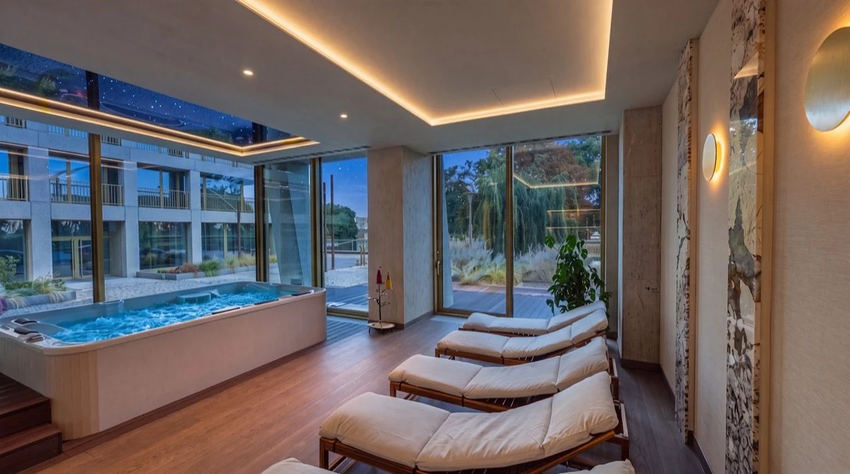 Strefa Wellness PONTI wieczorem: jacuzzi przy oknie i strop z gwiazdami